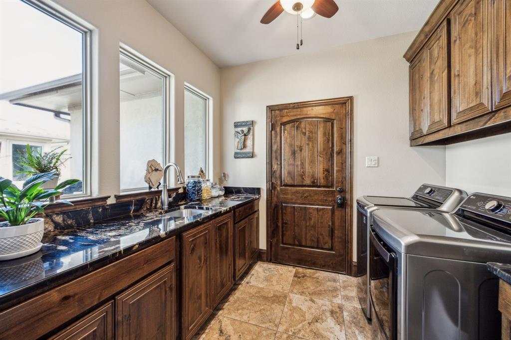 10761 County Road 2326 Terrell, TX 75160 - Photo 23 of 35 Laundry room with a sink, washing machine and dryer, stone finish flooring, ceiling fan, and cabinet space
