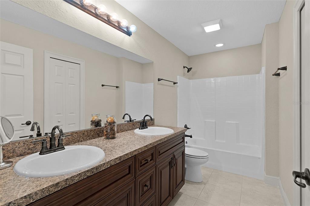 13 Malauka Radial Run Road Ocklawaha, FL 32179 - Photo 15 of 32 a bathroom with a granite countertop double vanity sinks a mirror a toilet and a tub