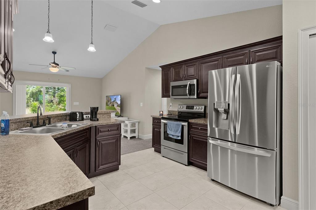 13 Malauka Radial Run Road Ocklawaha, FL 32179 - Photo 5 of 32 a kitchen with granite countertop stainless steel appliances and wooden cabinets