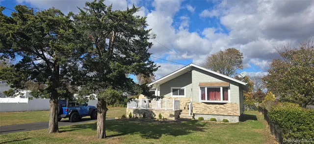 a view of a white house next to a yard with big trees