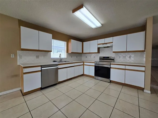a large kitchen with a stove a sink dishwasher and a refrigerator