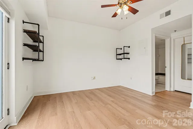 an empty room with windows and ceiling fan