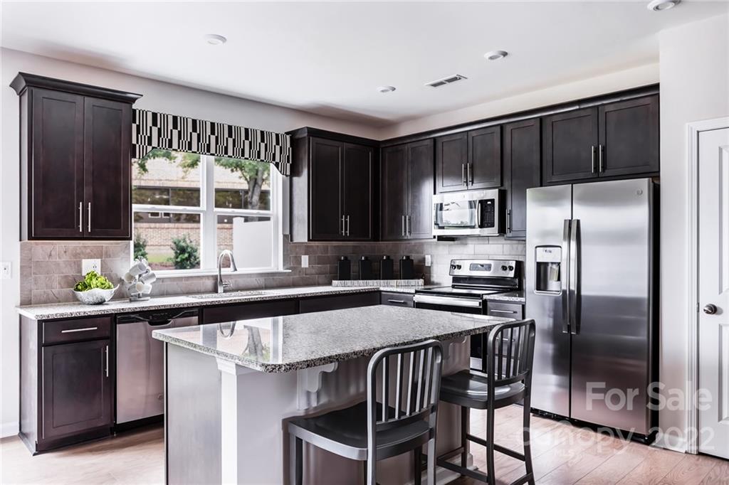 a kitchen with kitchen island granite countertop a sink stove and refrigerator