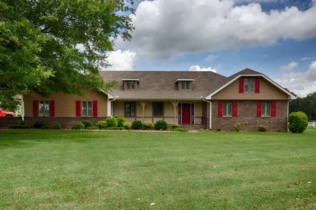 a view of a big house with a big yard and large trees