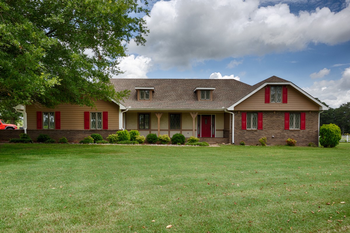 a view of a big house with a big yard and large trees