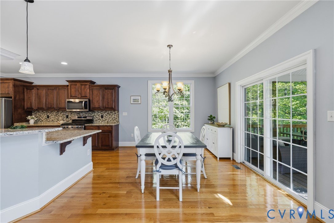 8825 First Branch Lane Chesterfield, VA 23838 - Photo 9 of 49 a dining room with wooden floor a chandelier a glass table and chairs