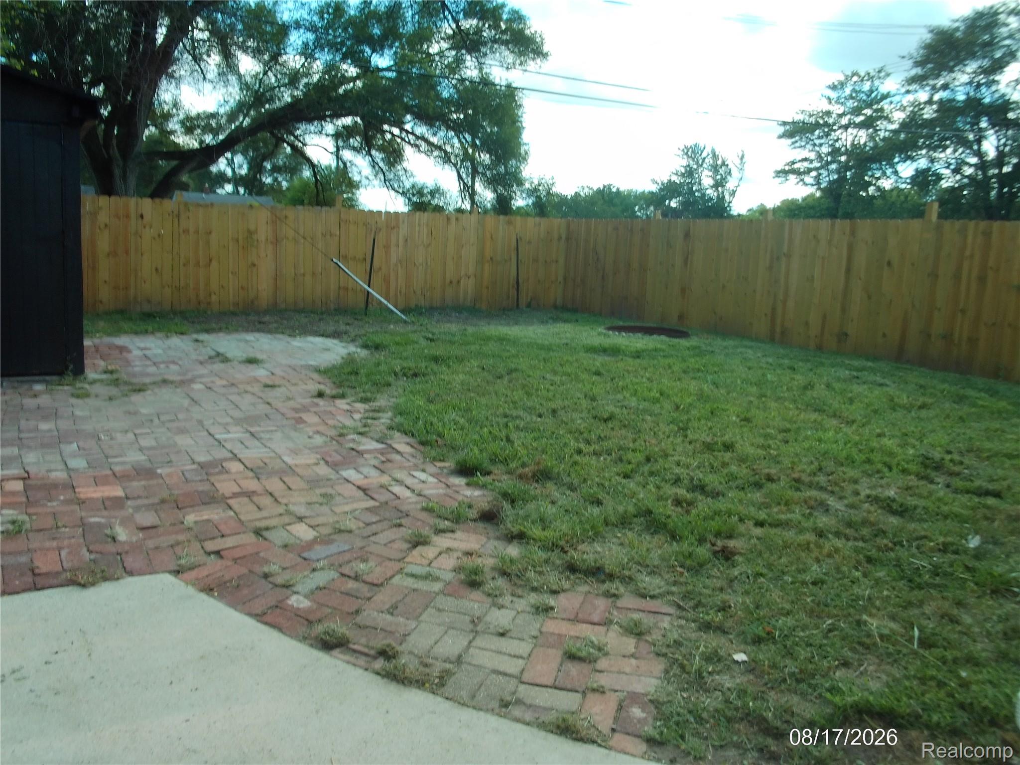 26445 Colgate Street Inkster, MI 48141 - Photo 29 of 35 Expansive backyard featuring a wood privacy fence, brick paver patio, and lush lawn