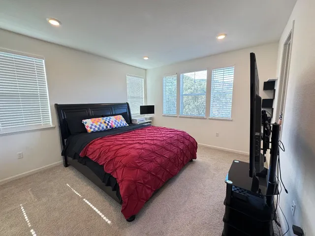 a bed sitting in a spacious bedroom next to a window