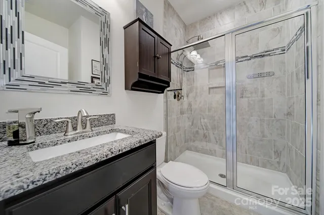 a bathroom with a granite countertop sink a toilet and shower