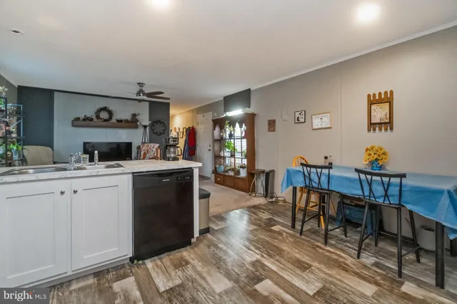 a open kitchen with stainless steel appliances granite countertop a stove a sink a dining table and chairs with wooden floor