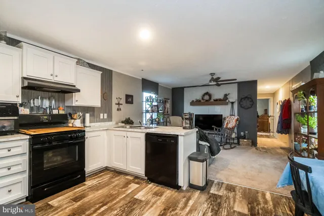 a kitchen with granite countertop a stove top oven a sink dishwasher and a fireplace with wooden floor