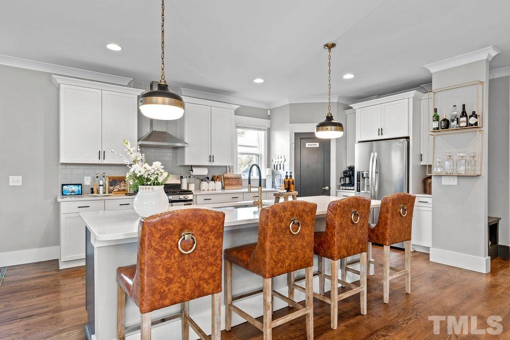 607 Bragg Street Raleigh, NC 27610 - Photo 12 of 44 a kitchen with stainless steel appliances granite countertop a refrigerator a sink dishwasher a dining table and chairs with wooden floor