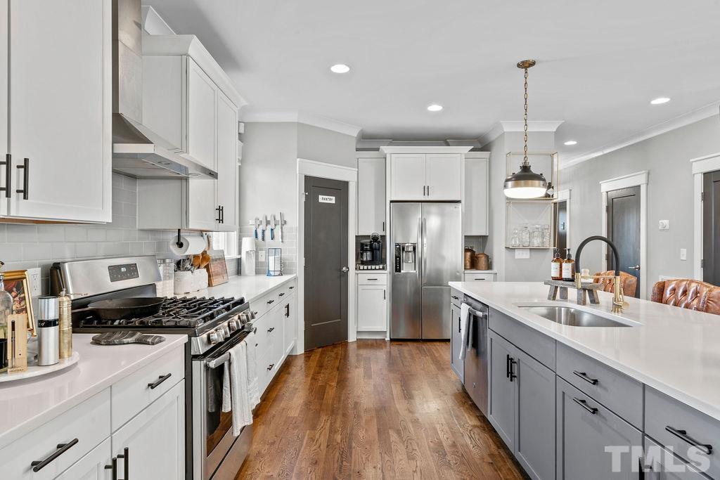 607 Bragg Street Raleigh, NC 27610 - Photo 13 of 44 a kitchen with stainless steel appliances a sink stove a refrigerator a oven a sink dishwasher and white cabinets with wooden floor