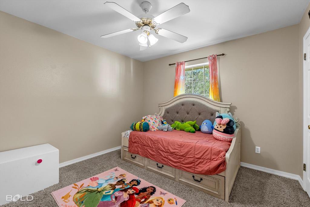 122 Ragan Lane Haughton, LA 71037 - Photo 19 of 34 Neutral wall paint, textured carpeting, a window with natural light, and a ceiling fan with integrated lighting