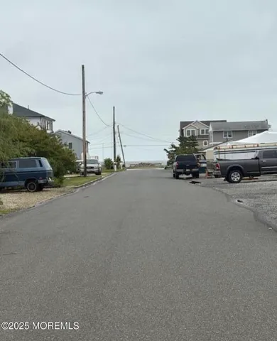a view of car parked on road with a view of house
