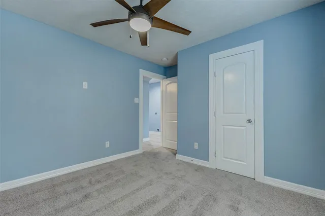 an empty room with ceiling fan and window