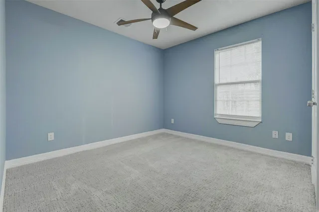 an empty room with a window and a fan