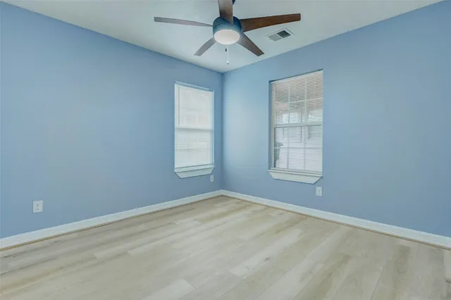 an empty room with windows and fan
