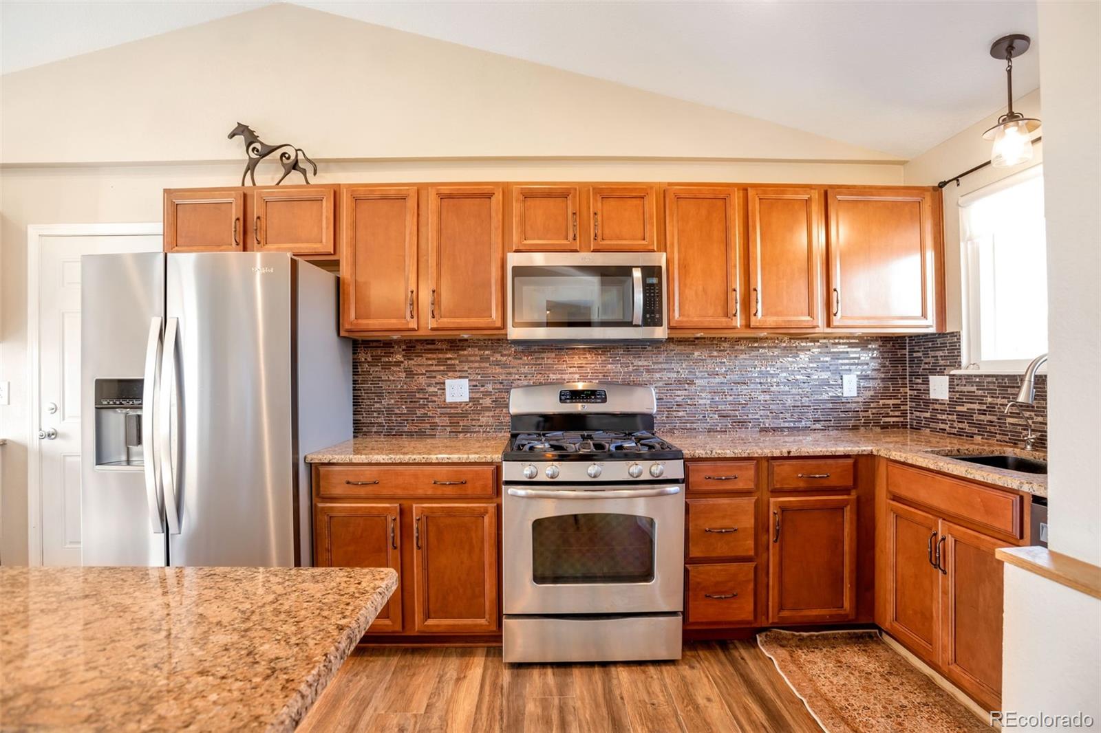 8678 Lariat Loop Elizabeth, CO 80107 - Photo 13 of 50 a kitchen with stainless steel appliances granite countertop a stove a sink dishwasher a refrigerator and a microwave
