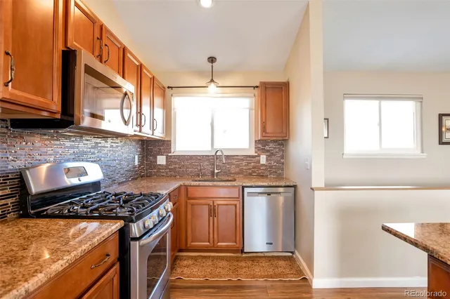 a kitchen with stainless steel appliances granite countertop a stove a sink and a microwave