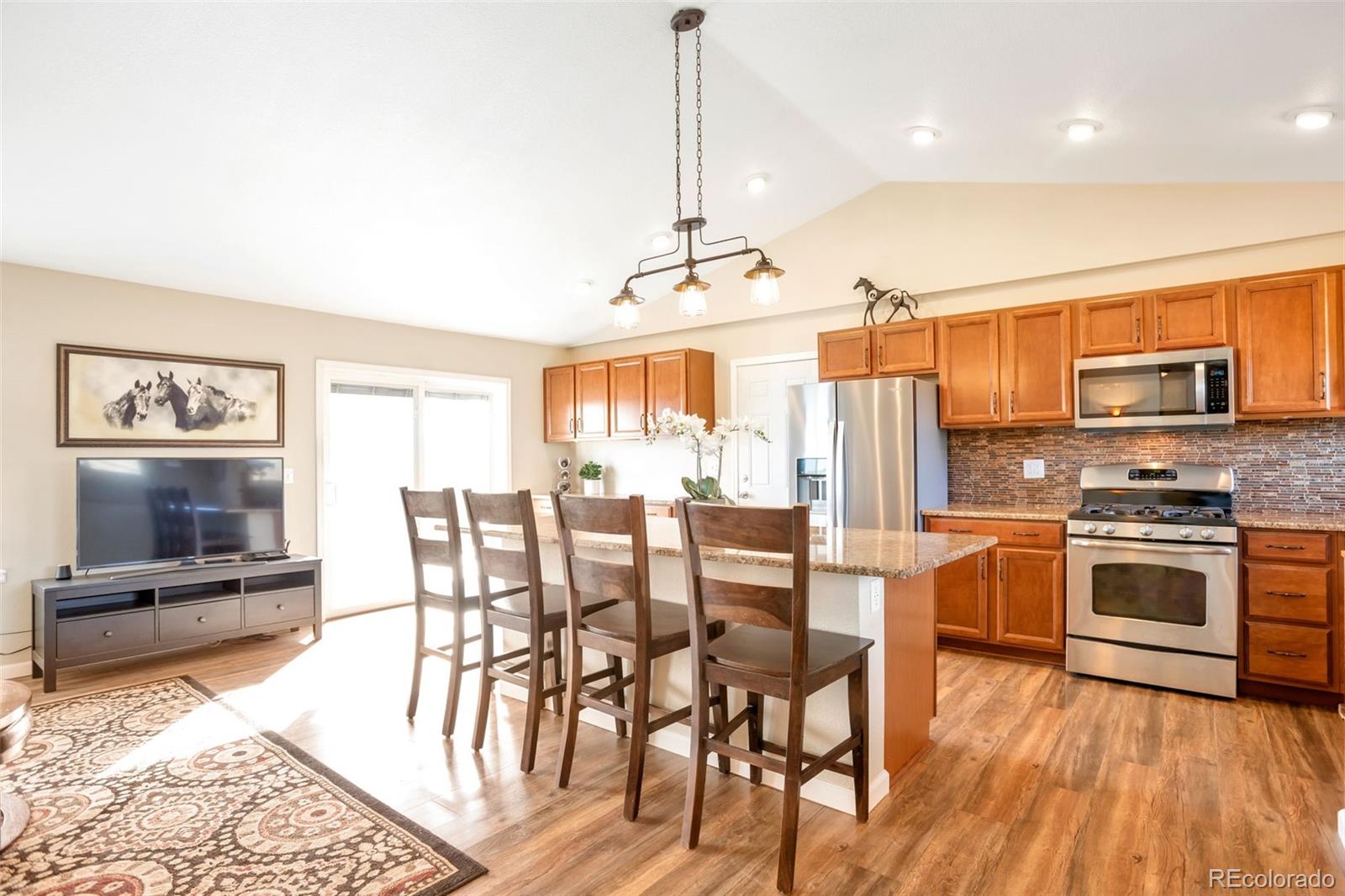 8678 Lariat Loop Elizabeth, CO 80107 - Photo 9 of 50 a kitchen with stainless steel appliances granite countertop a stove top oven a sink dishwasher a dining table and chairs with wooden floor