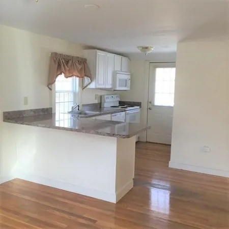 a kitchen with granite countertop a sink cabinets and wooden floor