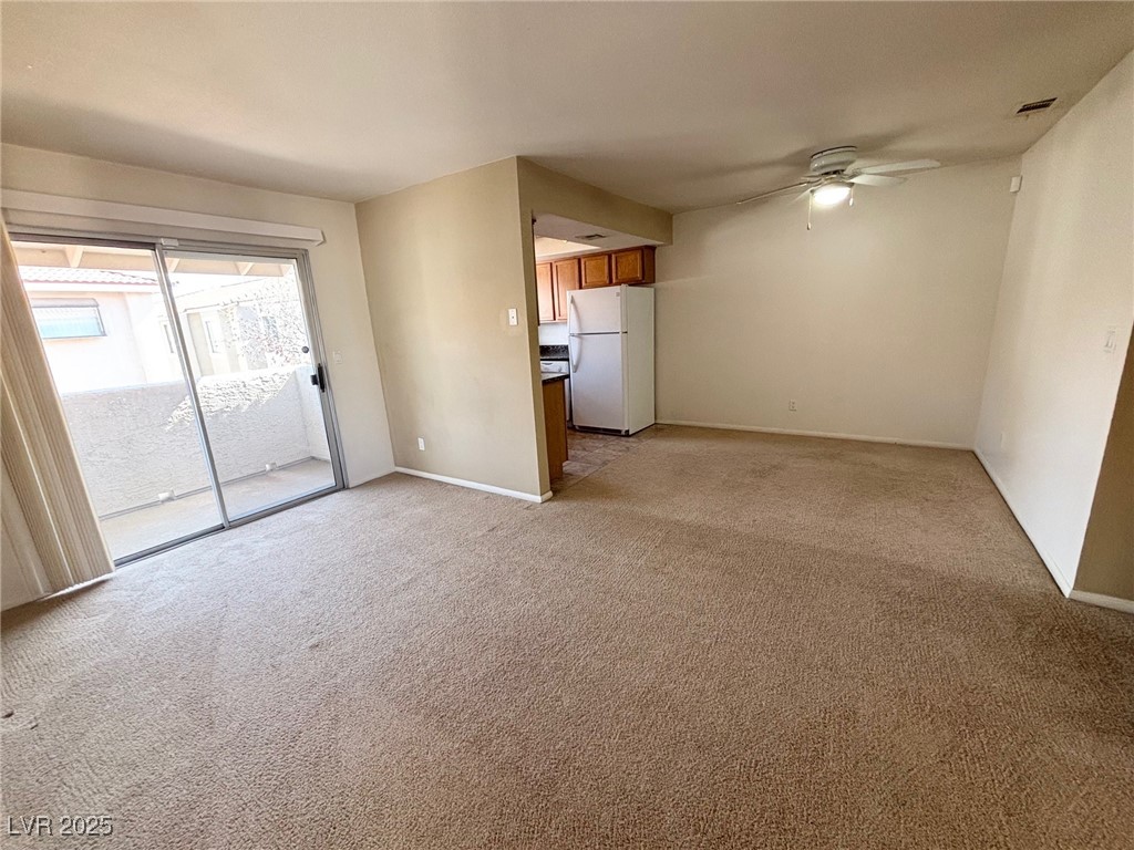 7300 West Pirates Cove Road, Unit 2054 Las Vegas, NV 89145 - Photo 7 of 16 Unfurnished living room featuring ceiling fan, light carpet, and baseboards