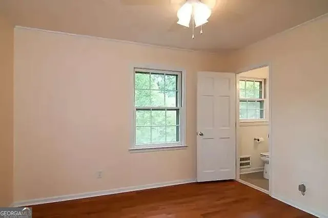 an empty room with wooden floor cabinet and windows