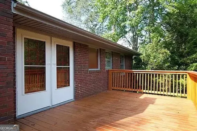 a view of backyard with deck and floor to ceiling window and wooden floor