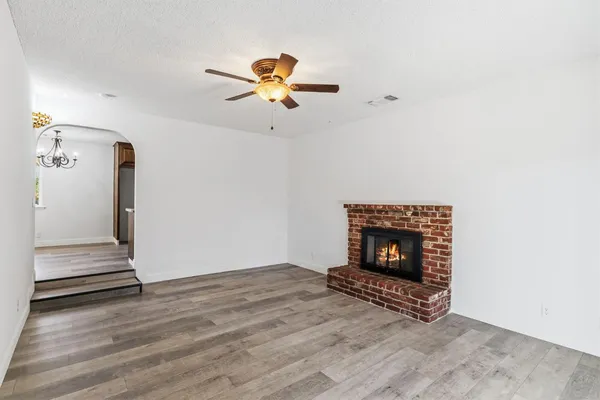 an empty room with wooden floor and ceiling fan