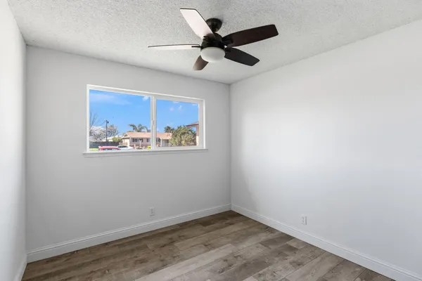 a view of an empty room with chandelier fan and a kitchen