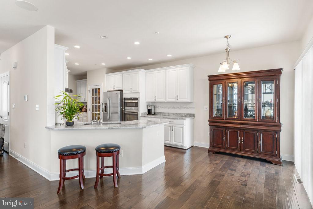 7608 Elmcrest Road Hanover, MD 21076 - Photo 4 of 41 a kitchen with kitchen island wooden cabinets and dining table
