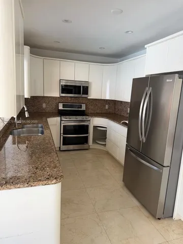 a kitchen with stainless steel appliances granite countertop a refrigerator a stove a sink and a microwave