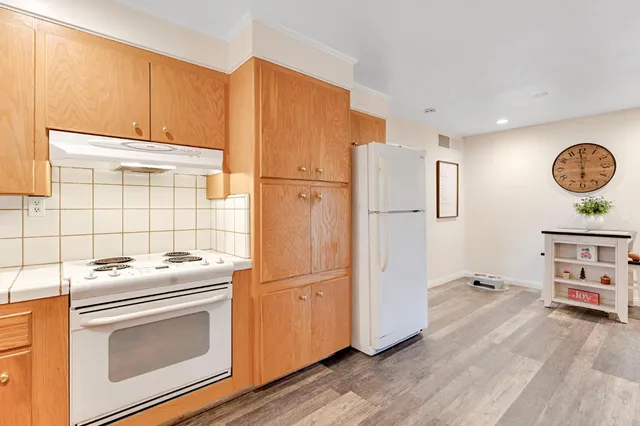 a kitchen with stainless steel appliances granite countertop a refrigerator stove and white cabinets with wooden floor