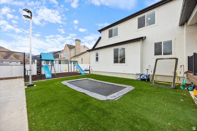754 West 400 North, Unit 29 Mapleton, UT 84664 - Photo 24 of 25 Back of property with a playground, stucco siding, a trampoline, a fenced backyard, and a patio