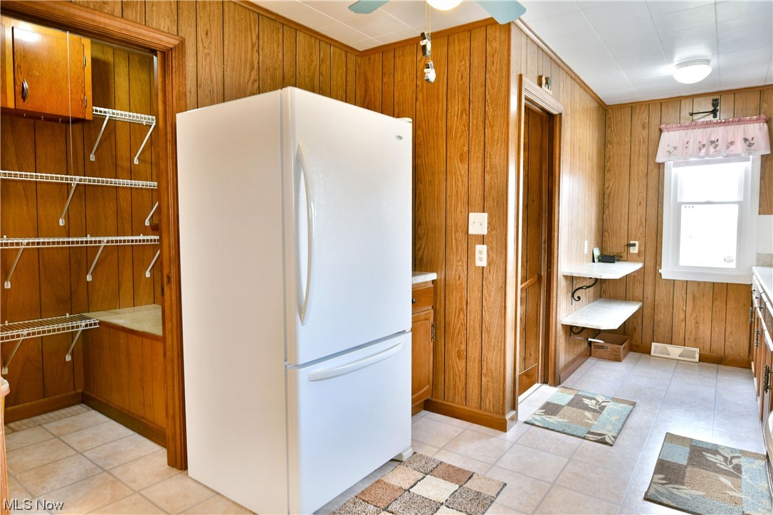 2713 Ridge Road Cortland, OH 44410 - Photo 13 of 35 Kitchen featuring light tile flooring, white refrigerator, ceiling fan, and wood walls