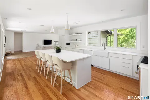 a kitchen with a table chairs wooden floors and a view of living room