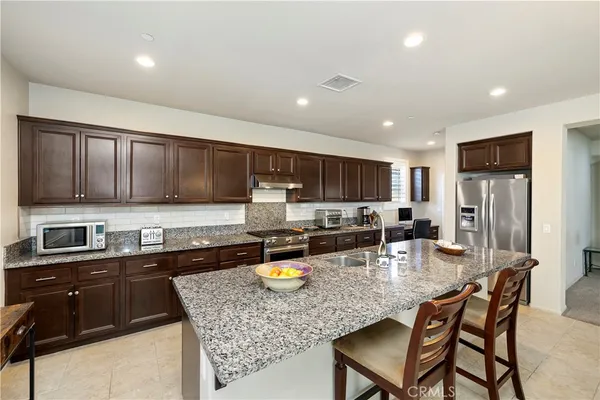 a kitchen with stainless steel appliances granite countertop a stove top oven a sink a stove a dining table and chairs