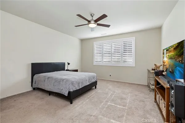 a living room with a bed furniture flat screen tv and a window