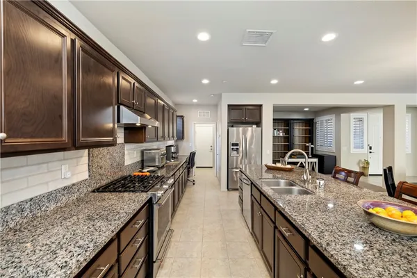 a kitchen with stainless steel appliances granite countertop sink stove refrigerator and cabinets