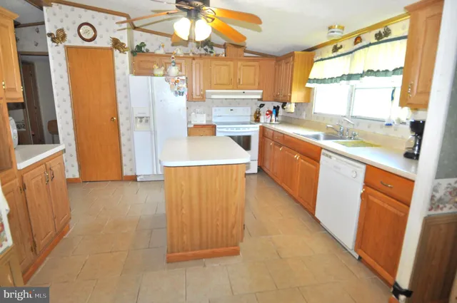 a large kitchen with a refrigerator a sink dishwasher a stove a washer and dryer next to a window