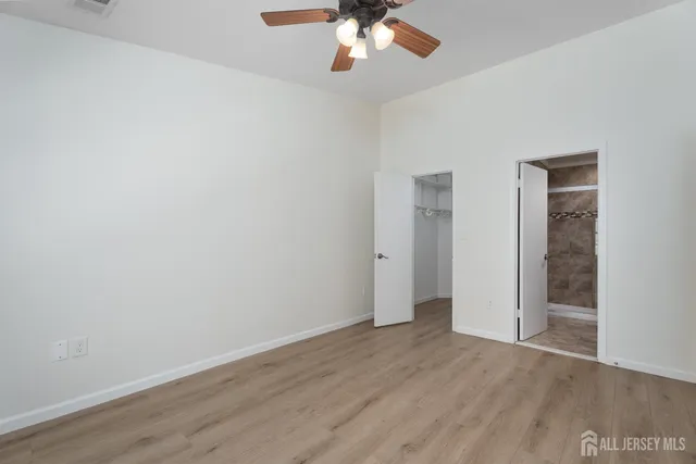 an empty room with wooden floor chandelier fan and closet area