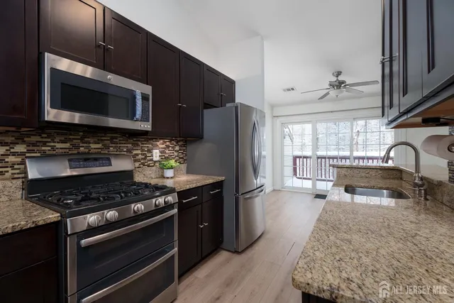 a kitchen with stainless steel appliances kitchen island granite countertop a stove refrigerator and microwave