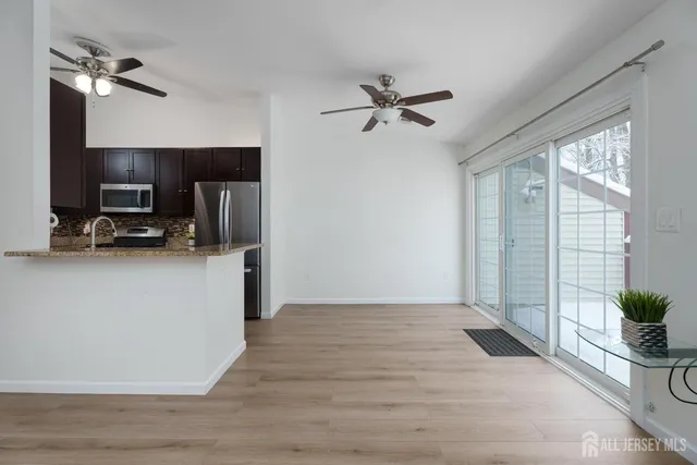 a view of a livingroom with a flat screen tv wooden floor and a ceiling fan