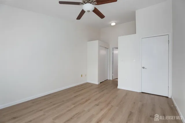 a view of empty room with wooden floor and ceiling fan