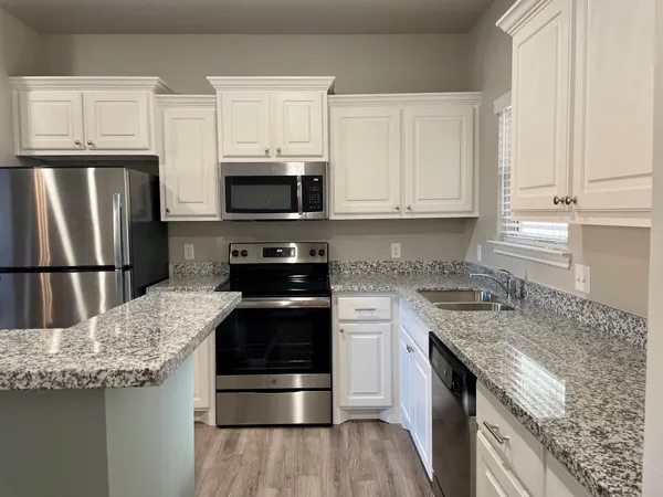 a kitchen with granite countertop a refrigerator stove and microwave
