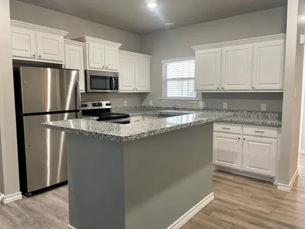 a kitchen with stainless steel appliances granite countertop a refrigerator a stove a sink and white cabinets
