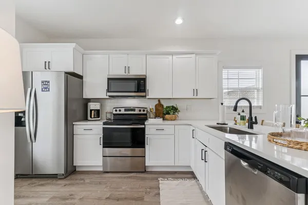 a kitchen with a sink white stainless steel appliances and cabinets