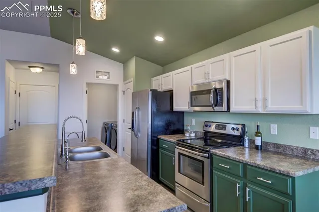 a kitchen with stainless steel appliances granite countertop a stove top oven a sink a refrigerator and white cabinets