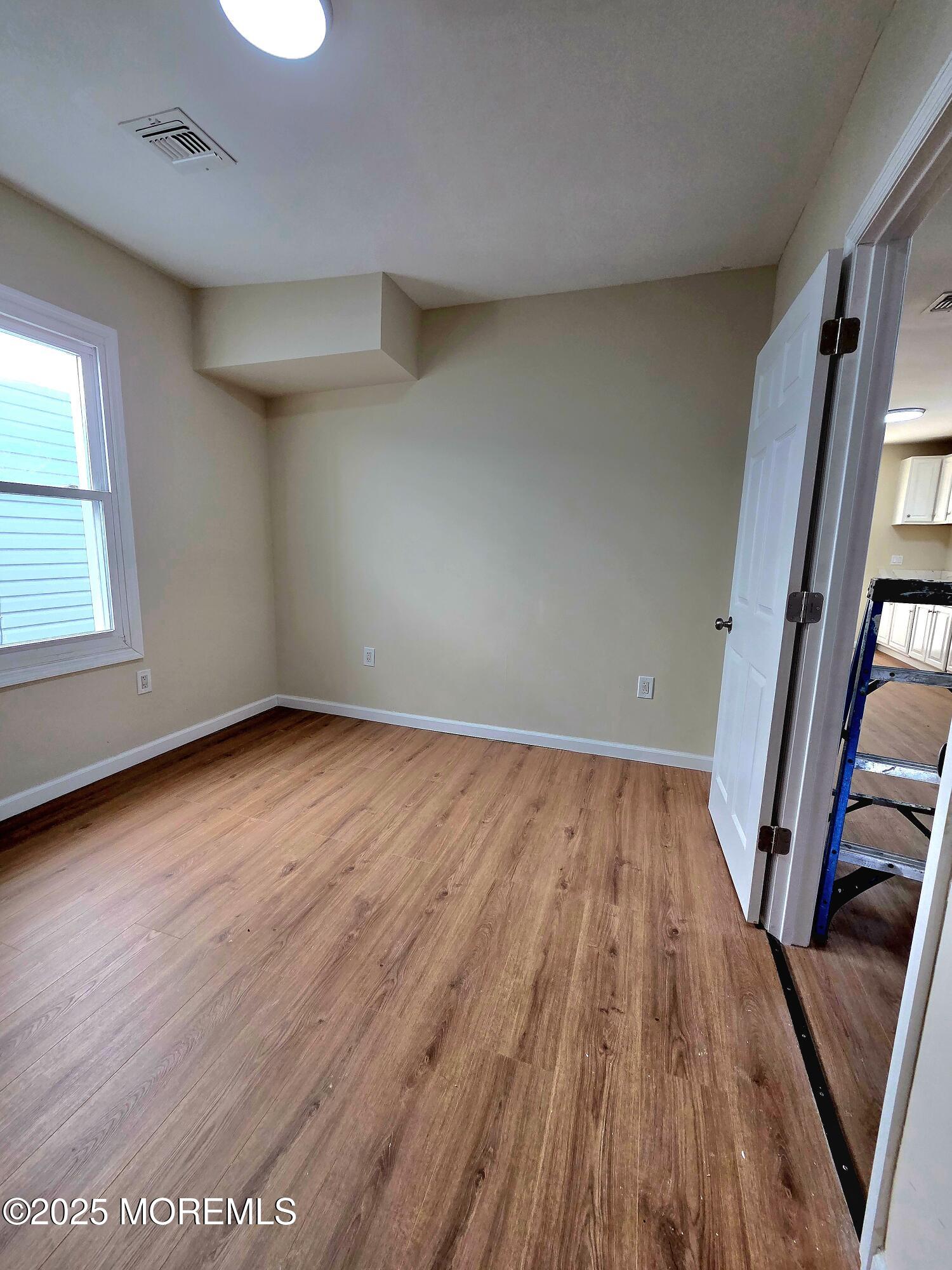 216 Delaware Street Elizabeth Port, NJ 07206 - Photo 21 of 40 an empty room with wooden floor and windows